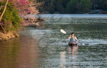 Caucasian man wearing PFD paddling towards the camera on a spring evening on a calm lake