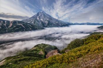 Mountains and volcanoes. Beautiful landscape of Kamchatka Peninsula: summer panoramic view of Mountain Range Vachkazhets, mountain lake and clouds in blue sky on sunny day. Eurasia, Russian Far East, 