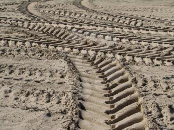 Traces of wheels of a tractor on sand. The filled soil on a platform.