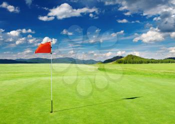 Golf field with red flag in the hole