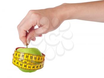Measuring tape and fresh green apple in hand on a white background