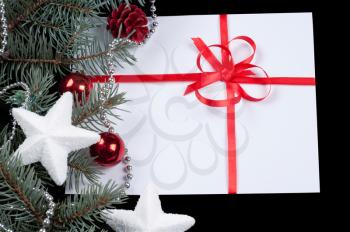 fir branch and card with a red ribbon on a black background