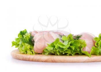 Raw chicken meat with green salad on a wooden board