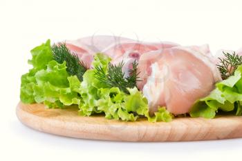 Raw chicken legs with green salad and dill on a wooden board