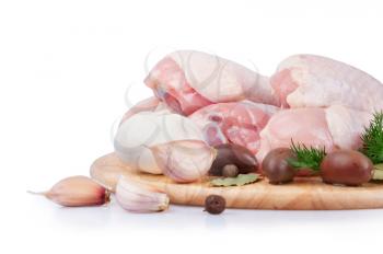 Raw chicken legs with olives and garlic on a wooden board