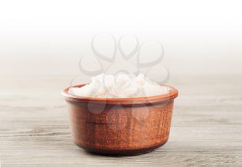 Aromatic bath salt in a clay cup on a wooden surface