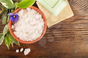 Aromatic bath salt in a clay cup and soap on a wooden background