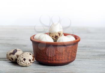 Boiled quail eggs in a clay dish on a wooden background