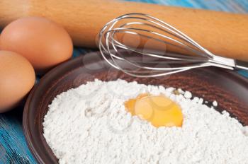 Eggs, flour and egg yolk on a blue wooden background