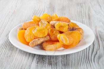 Dried fruits on a wooden background. Candied fruits, lemon, apricot, figs. Fruits in white plate.