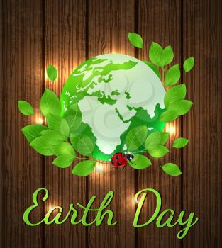 Planet Earth and green branch on a wooden background. Card for Earth Day.