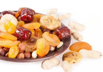 Dried fruits on a white background. Dates, lemon, apricots, figs and nuts in a clay plate. 