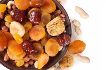 Dried fruits on a white background. Dates, lemon, apricots, figs and nuts in a clay plate. Top view.