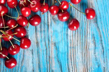 Red ripe sweet cherry on a blue wooden background. Top view.