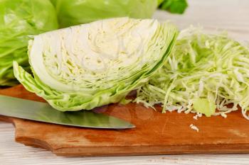 Fresh white cabbage and chopped cabbage for salad on a wooden cutting board. Vegetarian and healthy diet food concept. 