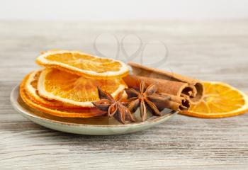 Dried orange slices, cinnamon and star anise in a plate. Spices for mulled wine on a wooden background.