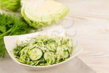 Fresh vegetable salad with cucumber and cabbage in a white plate.  Vegetarian and healthy diet food concept. 
