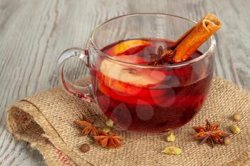 Mulled wine with spices and fruit on a wooden background. Traditional Christmas hot drink with red wine, apples, oranges and cinnamon