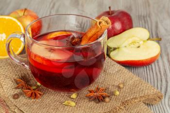 Mulled wine with spices and fruit on a wooden background. Traditional Christmas hot drink with red wine, apples, oranges, anise and cinnamon