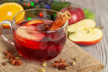 Mulled wine with spices and fruit on a wooden background. Traditional Christmas hot drink with red wine, apples, oranges, anise and cinnamon