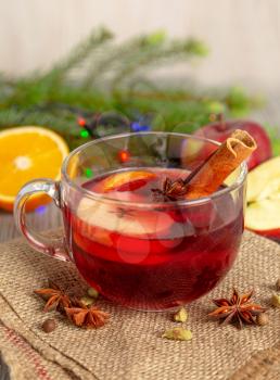 Mulled wine with spices and fruit on a wooden table. Christmas hot drink with red wine, apples, oranges and cinnamon. Tradition holiday menu.