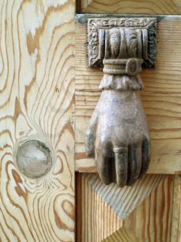 Old bronze knocker on a wooden door full of details