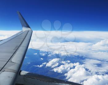 Wing of the plane on blue sky and clouds background