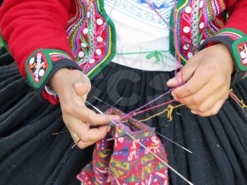 Close up of Peruvian lady in authentic dress spinning yarn by hand. (Peru)