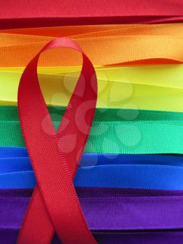 AIDS awareness red ribbon on gay flag background