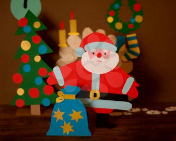 funny paper Santa Claus with bag of gifts in bright holiday clothes
