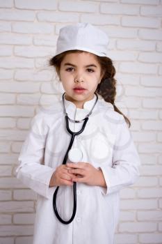 Little girl doctor in the white uniform with stethoscope