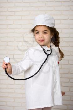 Little girl doctor in the white uniform with a stethoscope