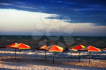 Empty beach with umbrellas in bad, stormy weather