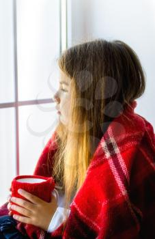 the little girl froze and wrapped herself in a blanket. Sits, looks out the window and drinks a hot drink