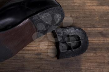old torn man's boot with a fallen heel on a wooden background