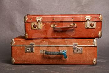 Old long out of fashion redhead closed suitcases on gray background