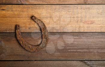 a very old and rusty horseshoe symbol of luck on a simple wooden background