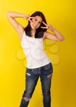 Young pretty girl in casual clothes dabbles and grimaces holding her fingers to her eyes on a bright yellow background