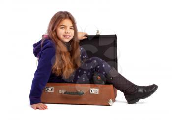 Little girl in shoes dabbles and climbs into a staggy suitcase