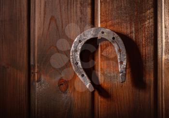 old horse horseshoe hanging horns down on a rusty nail on a dark wooden wall