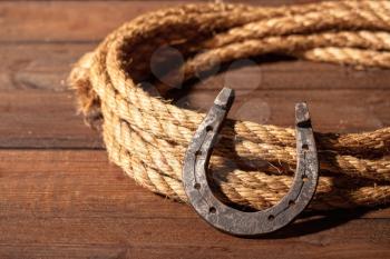 An old horseshoe lies next to a classic cowboy lasso on a dark wooden background.