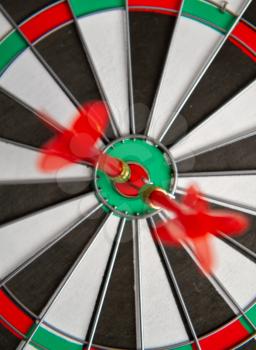 Close-up dart board with a red arrows that hit the center of the target