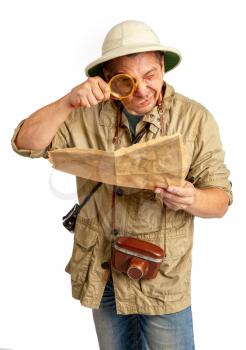 Adult tourist in tropical pith helmet and protective clothing looks into a magnifying glass on an old map.