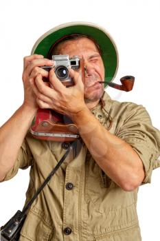 Adult Tourist in a tropical cork helmet and protective clothing with a pipe in his mouth photographs something on the old camera