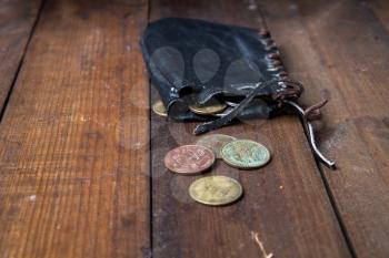 Old leather pirate wallet - a bag with small copper coins lying on a dark wooden surface