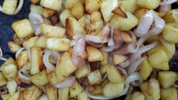 street food fried in a large metal pan over an open fire fried potatoes with onions