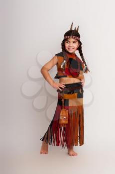 little native american girl in traditional dress posing on a light background