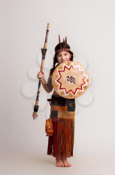 little Native American girl in traditional dress with a spear and a shield in her hands