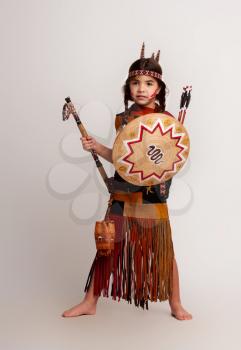 little indian girl in traditional dress with a tomahawk and a shield in her hands