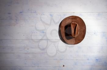 a classic brown cowboy hat hanging on the plank wall of an old barn